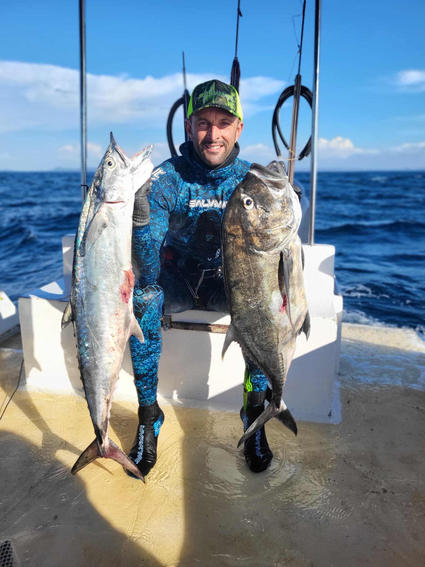 Rudy Levy en combinaison de chasse sous-marine, sur le bateau, avec ses prises du jour
